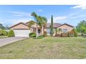 Charming single Gathering home with a two-car garage and beautiful landscaping with green grass and palm trees at 789 Kangaroo Ct, Deltona, FL 32738