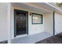 A close-up of a beautifully tiled front porch, featuring a black front door and a well-lit entryway at 10526 Fernando St, Orlando, FL 32825