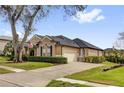 Side view of a tan home showing the two car garage, manicured lawn, and dark roof at 1415 Crocus Ct, Longwood, FL 32750