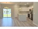 Open-concept kitchen featuring white cabinets, stainless steel appliances, and a central island with modern pendant lighting at 14222 Sw 48Th Ave Rd, Ocala, FL 34473