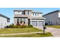 Charming two-story home featuring a stone facade, manicured lawn, and a two-car garage at 16008 Volterra Pt, Montverde, FL 34756