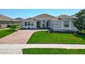 Charming single-story home featuring a well-manicured lawn, brick driveway, and inviting entrance at 16084 Black Hickory Dr, Winter Garden, FL 34787