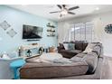 Cozy living room with light blue walls, a large sectional, and decorative shelves at 16084 Black Hickory Dr, Winter Garden, FL 34787