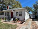 Side view of a cozy home with a brick-paved driveway leading to a detached garage, surrounded by lush greenery at 1919 Waldo St, Orlando, FL 32806