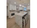 Modern kitchen with white cabinetry, quartz countertops, stainless steel appliances, and a large island with bar stools at 5153 Lido, Orlando, FL 32807