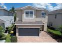 Two-story home with a two-car garage and brick driveway, complemented by lush landscaping at 7417 Marker Ave, Kissimmee, FL 34747