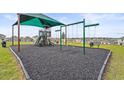 Community playground shaded by a green awning with swings and play equipment for children at 800 Griffon Ave, Lake Alfred, FL 33850