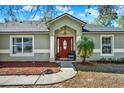 Welcoming front entrance with a striking red door, manicured landscaping and elegant columns at 1137 Stratton Ave, Groveland, FL 34736