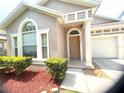Close-up of the home's entrance, showcasing the front door, sidelight window, and manicured shrubbery at 12863 Holdenbury Ln, Windermere, FL 34786
