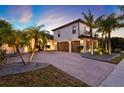 Spacious two-story home with a three-car garage, palm trees, and a brick paver driveway at 2680 Lookout Ln, Kissimmee, FL 34746