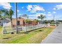 Single Gathering house on a sunny day with a white picket fence, palm trees and red driveway at 449 Martigues Drive, Kissimmee, FL 34759