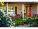 Charming front porch with a wooden chair, tidy landscaping, and a brightly painted orange front door at 5011 Dorian Ave, Belle Isle, FL 32812