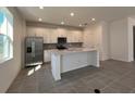 Modern kitchen featuring stainless steel appliances, white cabinets, and a large island with sleek countertops at 7028 Rolling Leaf Rd, Groveland, FL 34736