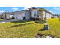 Light blue house featuring a two-car garage and a lush green lawn with beautiful landscaping at 7369 Sw 77Th Ave, Ocala, FL 34481