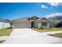 A well-maintained home featuring a neat front yard and a spacious driveway, set against a bright blue sky at 752 Trotters Dr, Eagle Lake, FL 33839