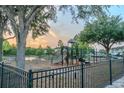 Community playground with slides, swings, and a secure fence for recreation and safety at 9620 Doris Ln, Orlando, FL 32829