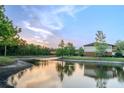 Scenic view of community pond reflecting the sky, surrounded by lush trees, and nearby residences at 9620 Doris Ln, Orlando, FL 32829