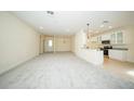 Spacious living area with neutral carpet flows into the adjacent kitchen area, creating an open layout at 1447 Kissimmee Way, Kissimmee, FL 34759