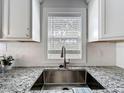 A bright and modern kitchen sink features granite counters and white tile backsplash at 1503 Holly Rd, Lakeland, FL 33801