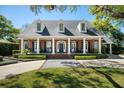 Stunning brick home with a charming front porch, featuring white columns, black shutters, and inviting curb appeal at 1911 Stonehurst Rd, Winter Park, FL 32789