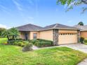 Inviting single-story residence with a neutral-toned exterior, stone detailing, manicured landscaping and brick paver driveway at 253 Lake Cassidy Dr, Kissimmee, FL 34759