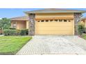 Lovely exterior showcasing a brick paver driveway and stone details around the garage at 253 Lake Cassidy Dr, Kissimmee, FL 34759