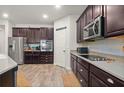 Modern kitchen featuring dark cabinetry, stainless steel appliances, and wood-look tile flooring at 3242 Irish Peach Dr, Winter Garden, FL 34787
