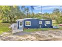 Exterior view of blue house featuring a ramp, bright door, and well-maintained landscaping at 10115 E Highway 316, Fort Mc Coy, FL 32134