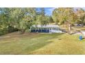 A single-story blue home sits on a spacious green lawn with mature trees and a metal roof at 10115 E Highway 316, Fort Mc Coy, FL 32134