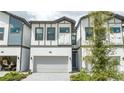 A white townhouse with a gray trim, a one car garage, and a gray stone driveway at 10443 Ebb Tide Ln, Orlando, FL 32821