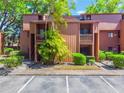 Exterior view of a two-story condo with palm trees, green shrubs, and balconies in a lush, landscaped community at 1068 E Michigan St # A, Orlando, FL 32806