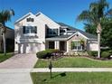 Charming two-story home featuring a lush, landscaped front yard, stone accents and a brick driveway at 1421 Arbitus Cir, Oviedo, FL 32765