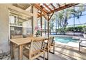 Outdoor dining area featuring a wooden table and seating with a view of the screened-in pool at 14266 Squirrel Run, Orlando, FL 32828