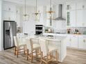 Modern white kitchen featuring stainless steel appliances, marble backsplash, and a center island with seating at 16354 Silver Grove Blvd, Winter Garden, FL 34787