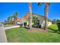 A yellow single-Gathering home featuring a red tile roof, palm trees, and a well-kept lawn at 248 Rosso Dr, Davenport, FL 33837