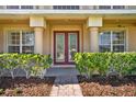 Elegant front entrance with red double doors, decorative columns, and manicured bushes at 4393 S Devon Ct, Kissimmee, FL 34746