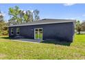 Dark blue house with a sliding glass door and a small patio and green grass at 4761 Sw 142Nd Place Rd, Ocala, FL 34473