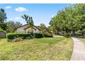 Well-maintained front yard featuring mature trees, trimmed hedges, and green lawn with sidewalk view at 10116 Pointview Ct, Orlando, FL 32836