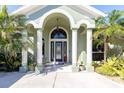 Welcoming front porch with an arched entry and classic columns, complemented by vibrant tropical foliage at 11139 Crooked River Ct, Clermont, FL 34711
