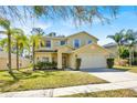 Two-story home featuring a two-car garage, a well-manicured lawn, and lush landscaping at 14740 Hartford Run Dr, Orlando, FL 32828