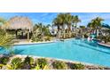 Inviting pool with lounge area, lush landscaping, and a thatched roof gazebo at 1551 Observer Ln, Davenport, FL 33896