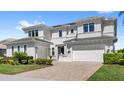 Elegant two-story home featuring manicured landscaping, a brick-paved driveway, and a three-car garage at 15633 Panther Lake Dr, Winter Garden, FL 34787