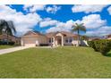 Beautiful one-story home with a lush green lawn, two-car garage, and manicured landscaping on a partly cloudy day at 2712 Pearl Court, Kissimmee, FL 34743