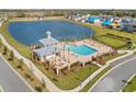 Aerial view of a resort-style pool with a pavilion, lounge chairs, and views of a serene lake at 2861 Willowseed Ln, St Cloud, FL 34772
