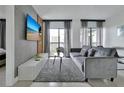 Cozy living room with a gray sofa, television, and access to a balcony at 6165 Carrier Dr # 3701, Orlando, FL 32819