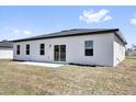 Back view of home, showing a concrete patio with a well-manicured backyard at 13584 Sw 43Rd Cir, Ocala, FL 34473