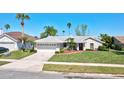 Charming single-story home with a well-manicured lawn and a two-car garage, complemented by palm trees at 14772 Eagles Crossing Dr, Orlando, FL 32837
