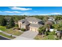 Well-maintained home featuring a three-car garage, stone veneer, manicured lawn, and lush plantings under a blue sky at 2015 Sandy Garden Ln, Winter Garden, FL 34787