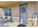 Inviting front porch with seating, decorative wreath, welcome mat, and stone accents creating a warm and welcoming entrance at 211 Lazio Cir, Debary, FL 32713
