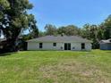 Back exterior view of the single-story home with large backyard, sliding glass doors, and neutral paint at 120 S Chandler Ave, Deland, FL 32724